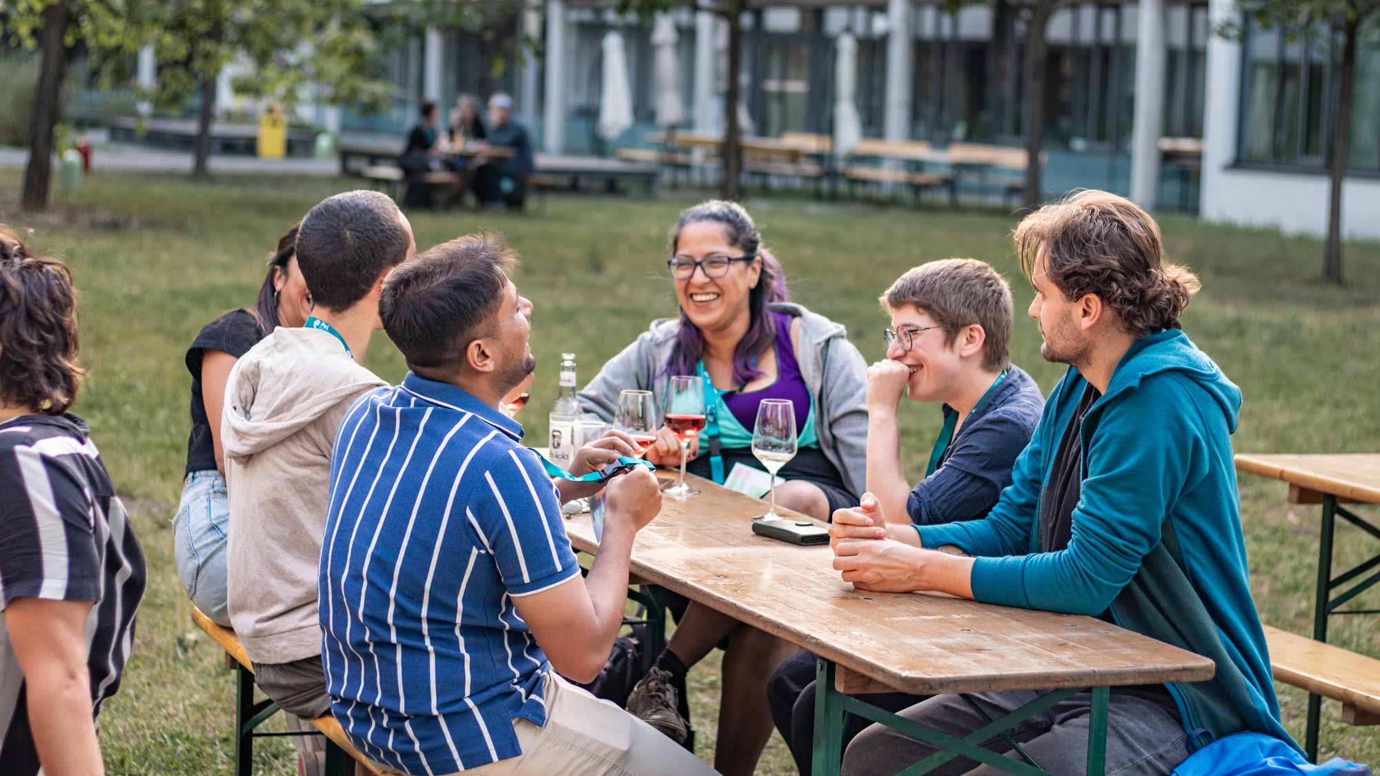 Students sitting on a table outside, chatting and having a drink